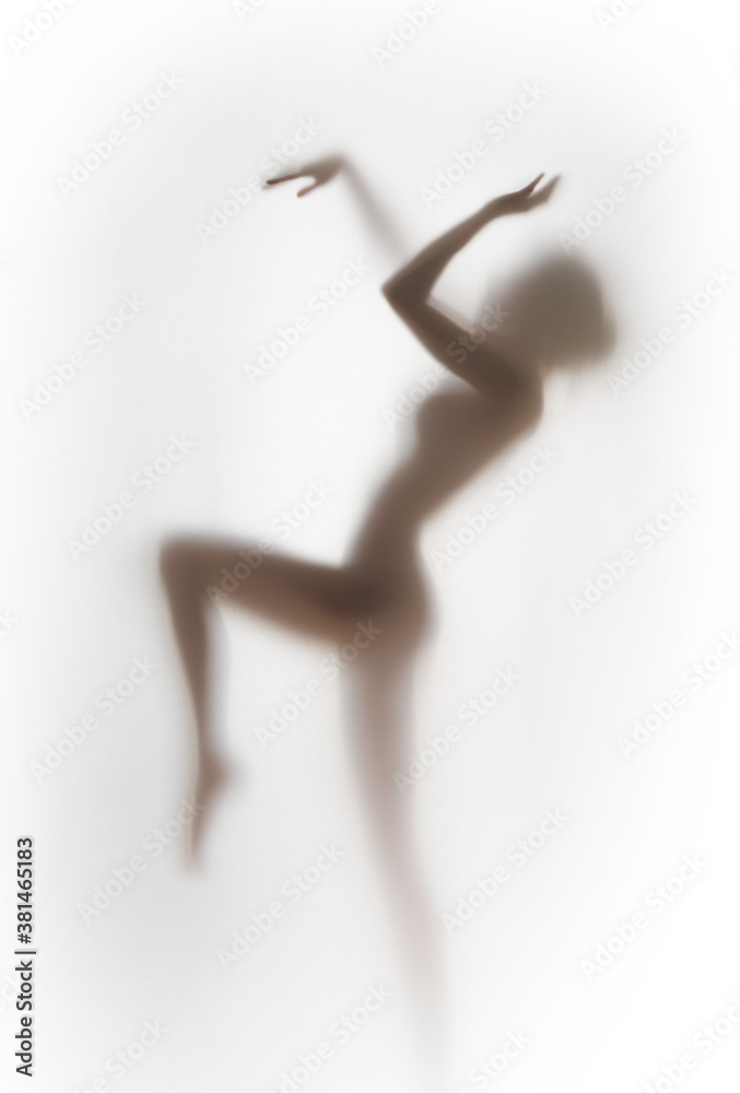 Pretty female human dancing body shape silhouette behind a white glass like curtain.