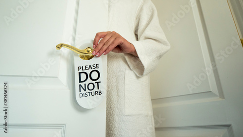 Tablou pe pânză A man's hand hangs a sign on the door of the hotel room with a request not to di