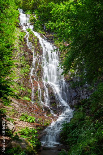 Powerful Pilj waterfall on Old mountain (Stara planina) in Serbia, cascading down the wet, red rocks and surrounded by vivid green trees