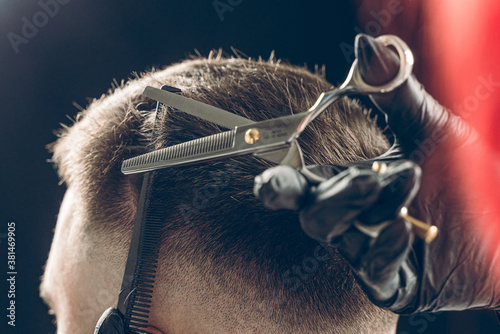 Cropped shot of barber cutting hair of customer with scissors