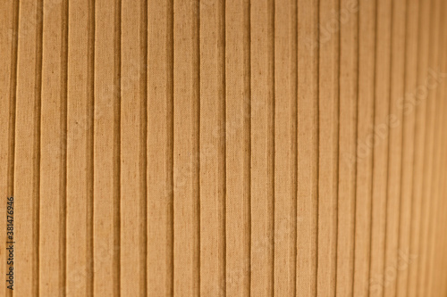 Close-up of an orange and lit fabric surface. Vertical striped pattern. Abstract high resolution full frame textured background. Shallow depth of field.