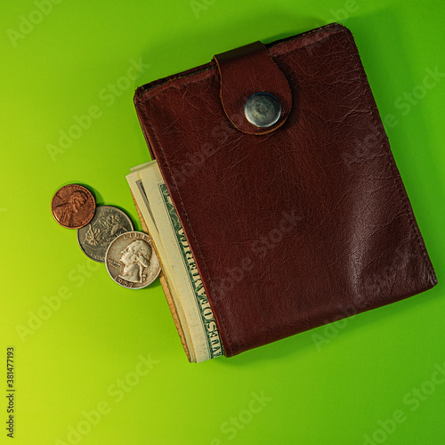 Partmone with paper dollar bills and coins lies on a green background. photo