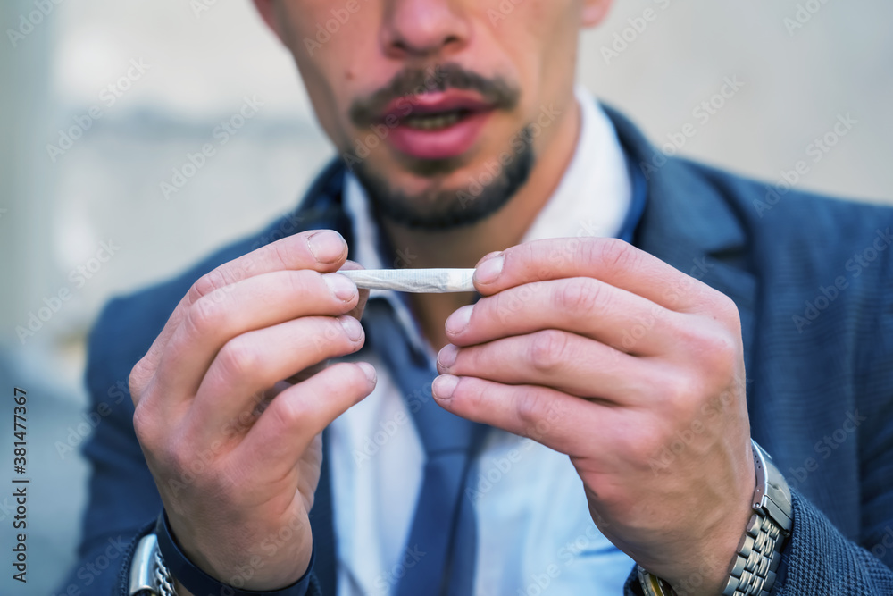 Portrait of the man holding real rolled marijuana or cannabis cigarette. Portrait of the man holding real rolled marijuana or cannabis cigarette.