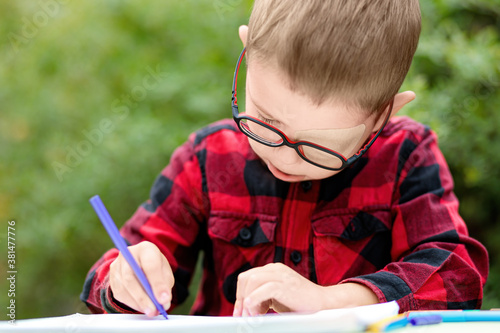 Slika na platnu Llittle boy draws in the garden (outdoors, not in the studio)