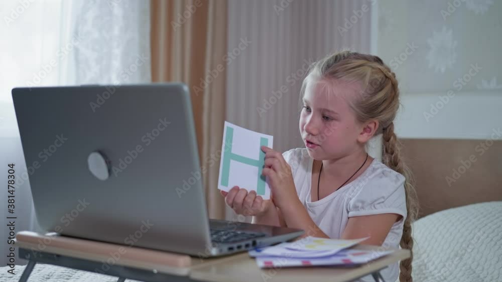 homeschooling child, pupil girl learns through online communication with the teacher while sitting with laptop computer in room in coronavirus times homeschooling child, pupil girl learns through online communication with the teacher while sitting with laptop computer in room in coronavirus times