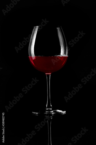 Wine glass with red wine isolated on black background photo