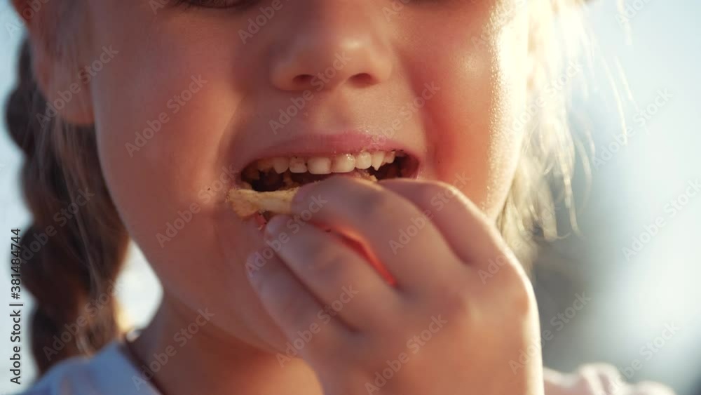 child eating chips close-up face. kid resting in the park eating chips. little girl resting on a picnic in the park eating potato chips. lifestyle kid dream concept child eating chips close-up face. kid resting in the park eating chips. little girl resting on a picnic in the park eating potato chips. lifestyle kid dream concept