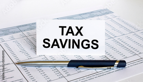 Text Tax Savings on white card with blue metal pen on financial table