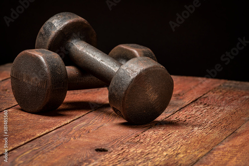 vintage rusty iron dumbbells on grained barn wood background - fitness concept