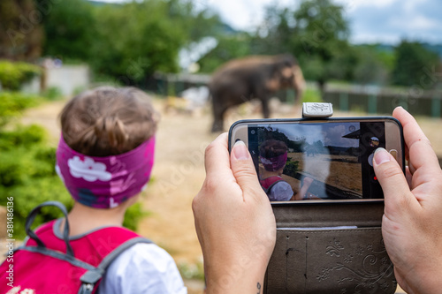 Kind im Zoo mit Smartphone fotografieren photo