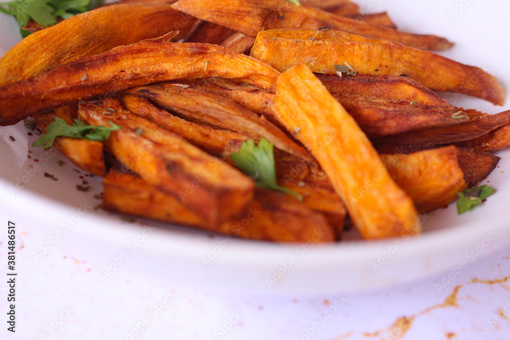 Home made freshness roasted sweet potatoes wedges on marble background Home made freshness roasted sweet potatoes wedges on marble background