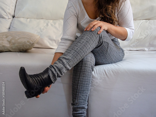 woman sitting on sofa taking off her shoe