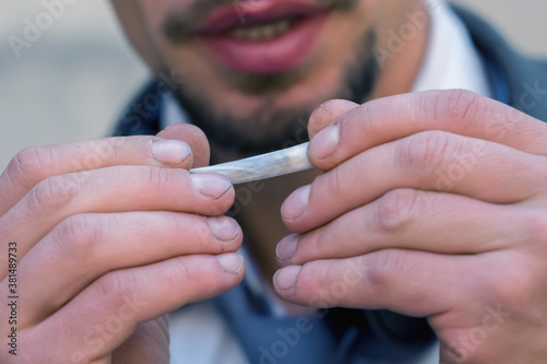 Close up man holding real rolled marijuana or cannabis cigarette. Selective focus.