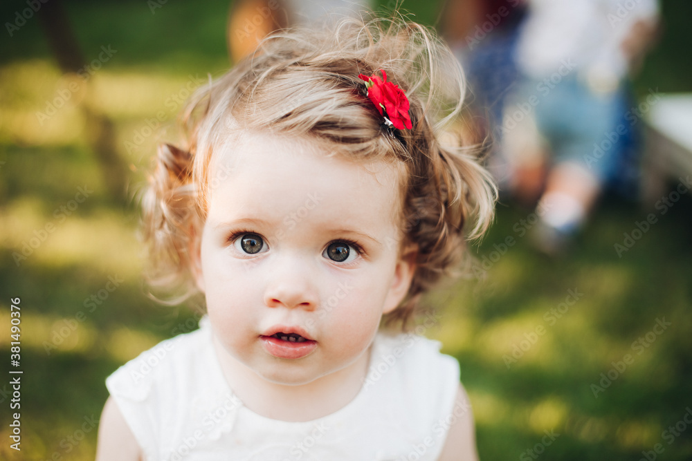 Beautiful caucasian little girl with short wavy fair hair in white dress in the garden Beautiful caucasian little girl with short wavy fair hair in white dress in the garden