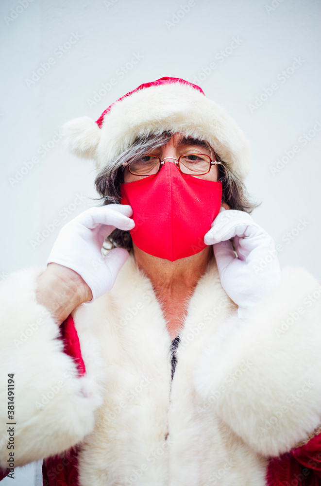 Obraz premium Santa Claus walking through the streets of the city of MadridSanta Claus putting on a mask in the city of Madrid.