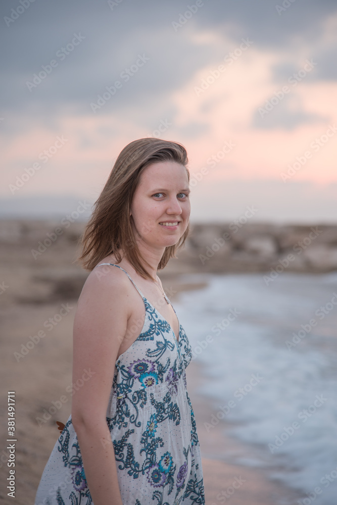 Mujer joven paseando en la playa a la puesta de sol Mujer joven paseando en la playa a la puesta de sol