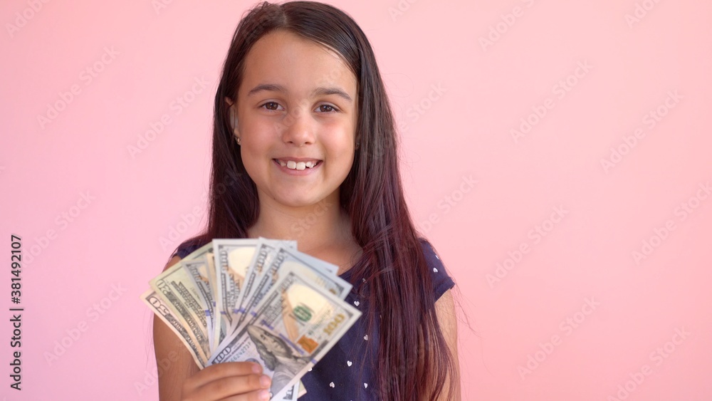 Cute little girl holding dollars, isolated over pink Cute little girl holding dollars, isolated over pink