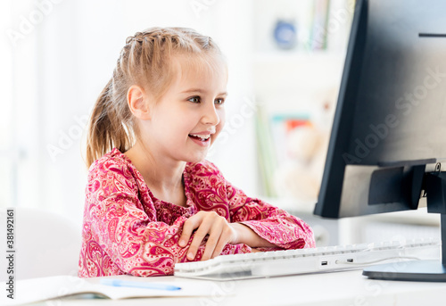 Smiling little girl at computer desk