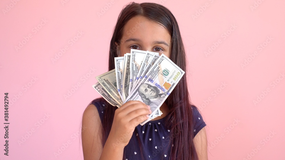 Cute little girl holding dollars, isolated over pink Cute little girl holding dollars, isolated over pink