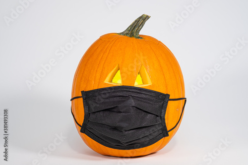 Carved Jack 'O Lantern wearing a Covid 19 face mask isolated on a white background