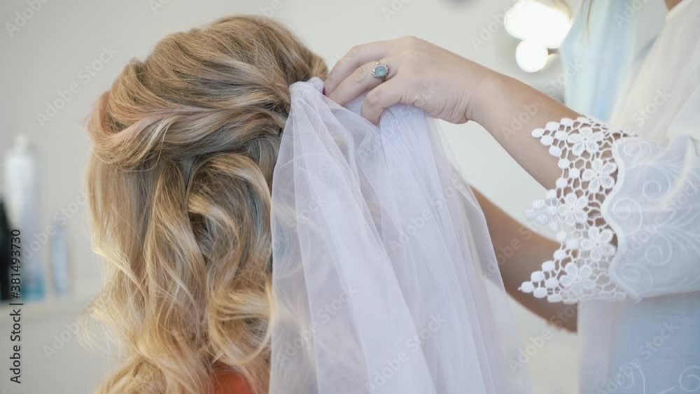 Hairdresser fix the veil on the bride's hairstyle