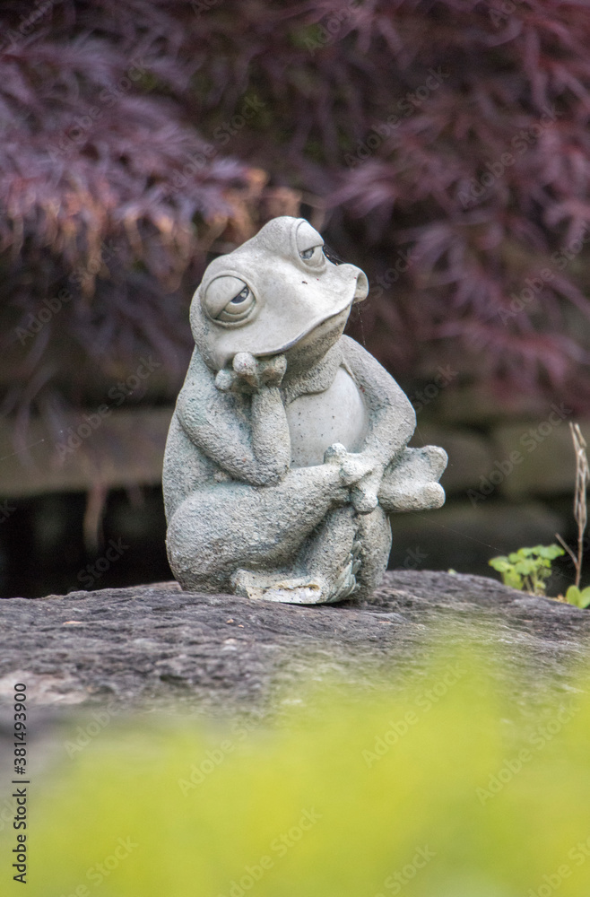 Obraz premium Thinking frog sculpture sitting by a pond