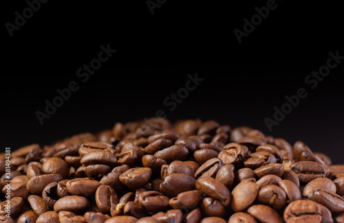 Coffee beans on a black background. Heap of coffee beans. Poured coffee close-up
