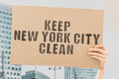 The phrase " Keep New York City clean " on a banner in men's hand with blurred background. Problem. Rubbish. Streets. Outdoor. Protest. Movement. Pollution