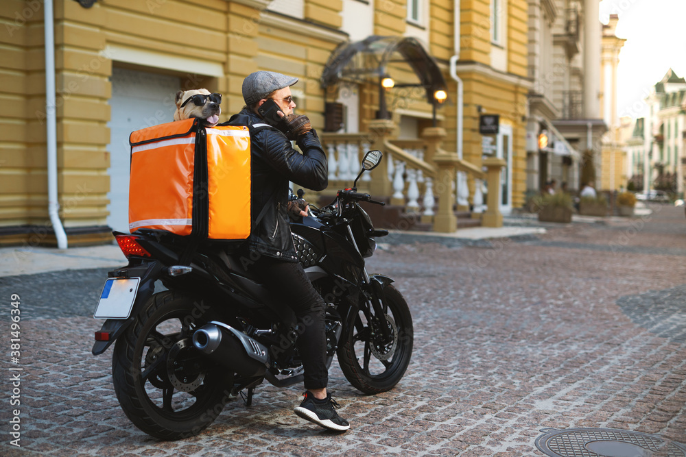 Man on motorbike with the dog inside special thermo bag for delivery food on the street.Food delivery service.