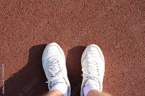 men's feet in white socks and sneakers on a sports treadmill.