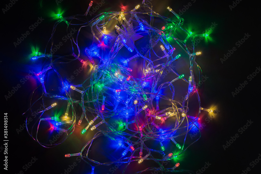 Christmas garland glows beautifully on a black background. Horizontal photo. Christmas garland glows beautifully on a black background. Horizontal photo.