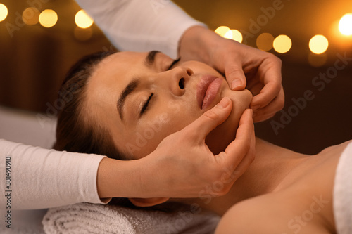 Relaxed woman getting healing face massage at spa