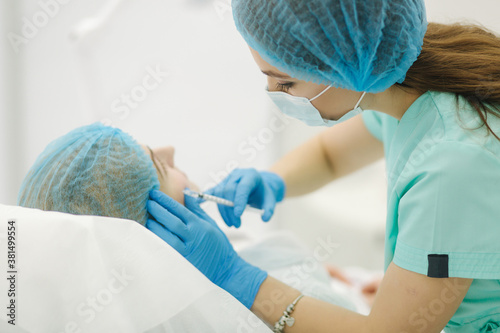 Hands of cosmetologist making injection in face  lips. Young woman gets beauty facial injections in beaty clinic. Face aging  rejuvenation and hydration procedures. Aesthetic cosmetology. Beauty salon