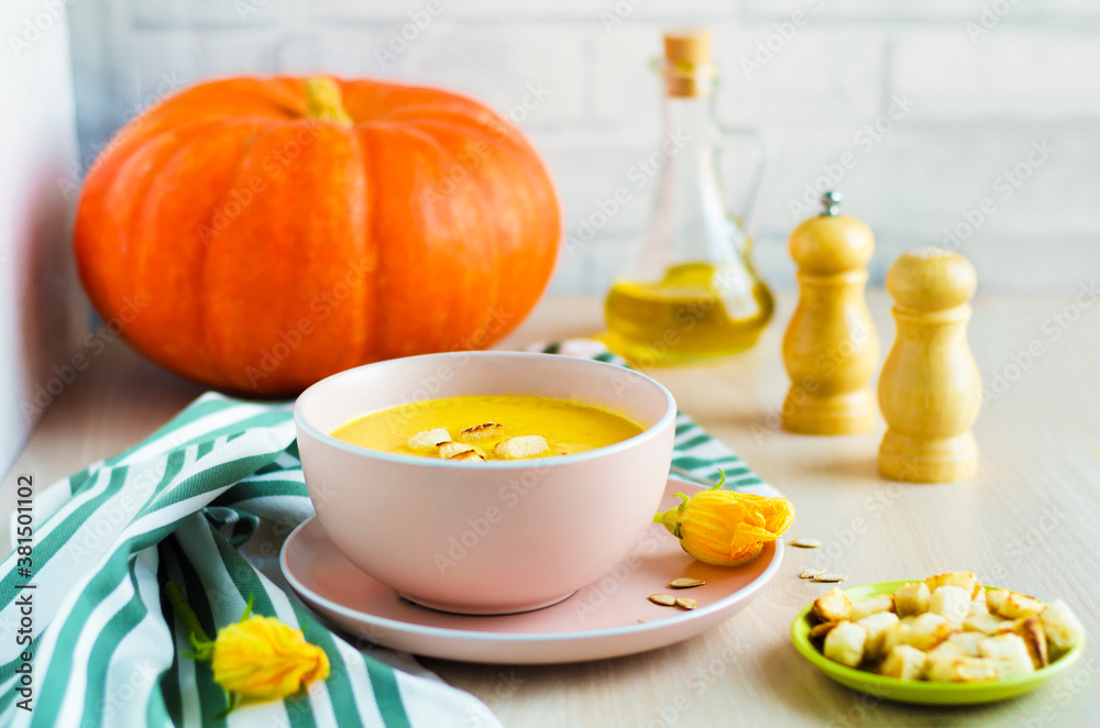 creamy pumpkin soup with vegetables, seeds and croutons in a bowl on light wooden background. Thanksgiving Day. traditional autumn dish, menu on the table. soft focus