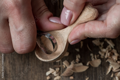 Fényképezés Handmade wooden utensils, top view female hands carve a wooden spoon with stock-