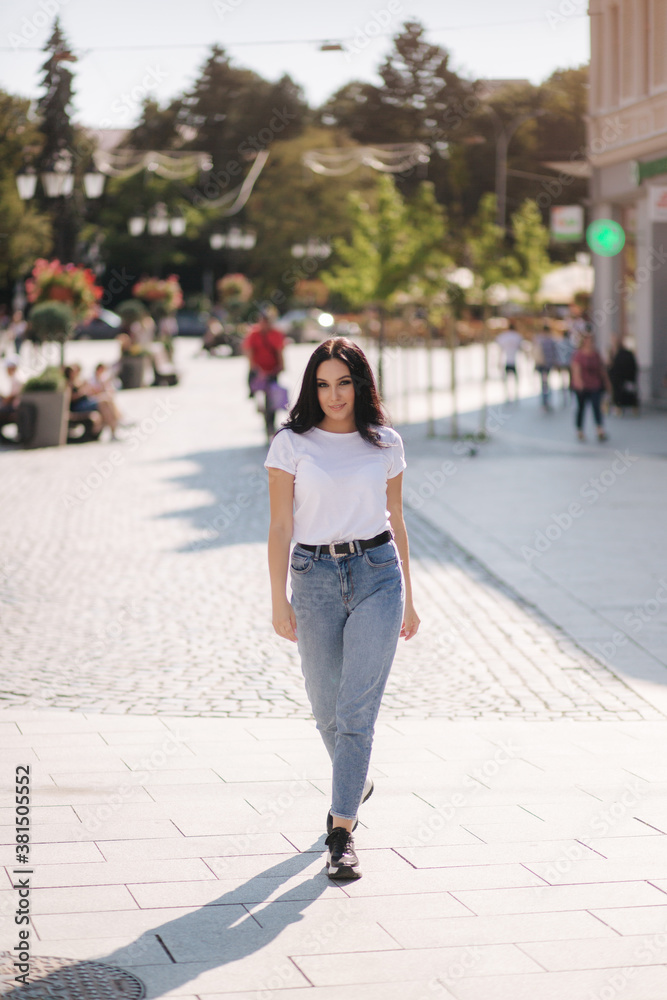 Attractive young woman in white shirt and jeans walking in the city