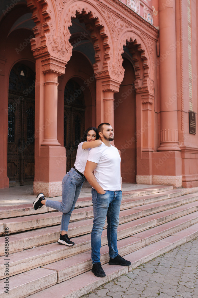 Two belowed people walking in the city. Beautiful couple in denim and white t-shirt have fun