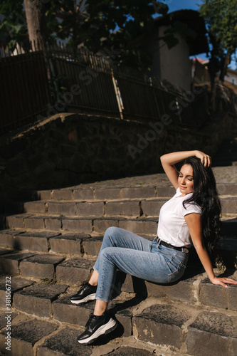 Sexy woman in denim sits on stairs in the city. woman with beautiful smile