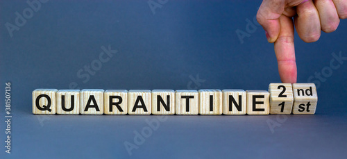 Male hand turns cubes and changes the expression 'quarantine 1st' to 'quarantine 2nd'. Beautiful grey background, copy space. Covid-19 pandemic concept.