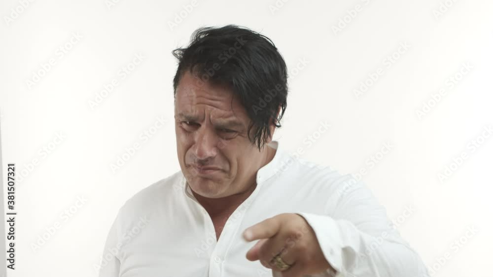 Close-up of emotional middle-aged man in white t-shirt, with golden ring, feeling betrayed or sad, pointing finger at camera to blame someone, standing over white background