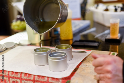 Creative occupation of candle making showing the pouring of liquid wax into jars