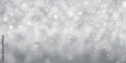 Christmas background of complex big and small falling snowflakes in gray colors with bokeh effect