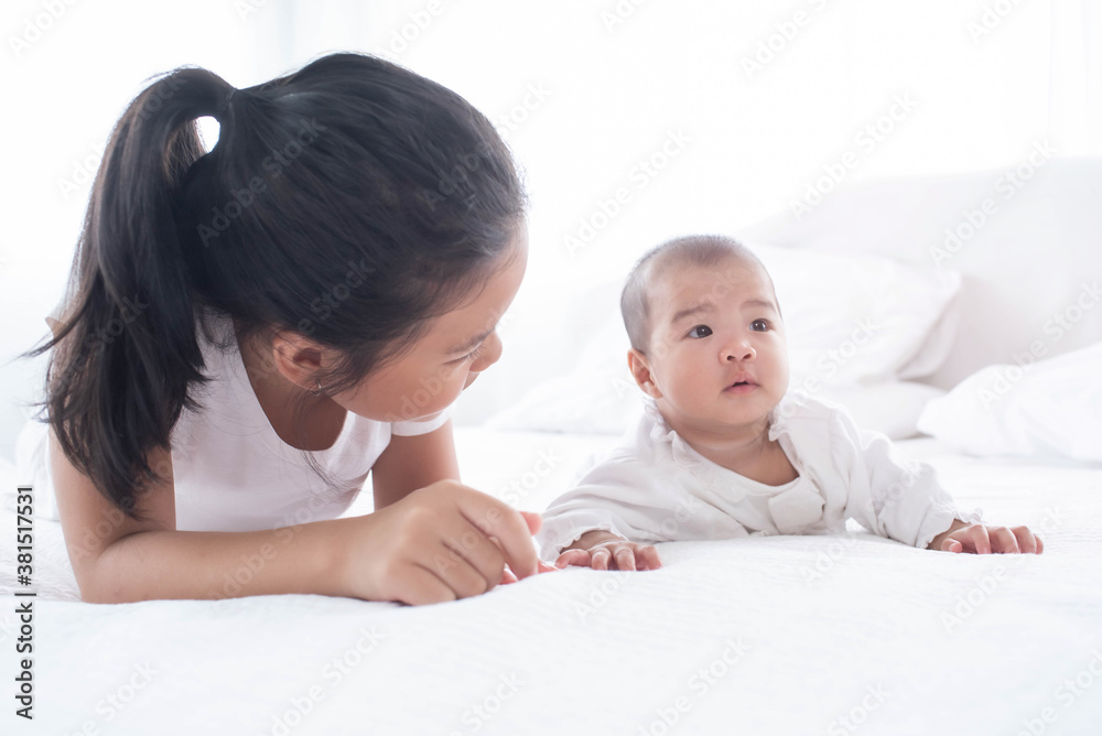 family with children at home. love, trust and tenderness..little sister hugging her newborn brother. toddler kid meeting new sibling. cute girl and new born baby boy relax in a white bedroom.