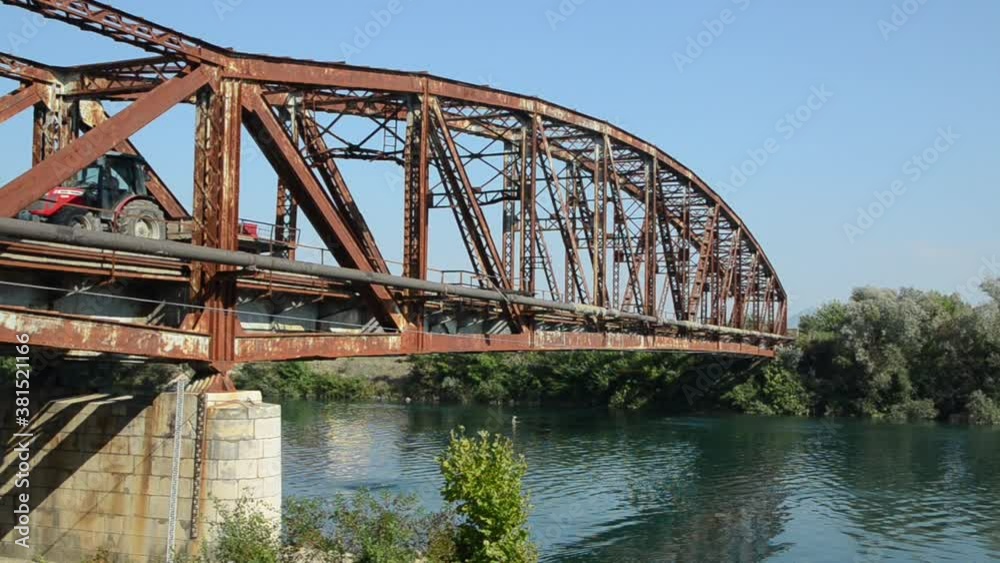 Old rusty bridge over the river. Transportation. Old metal bridge in nature. Border crossing. Steel bridge across the river against blue sky.
Old rusty bridge over the river. Transportation. Old metal bridge in nature. Border crossing. Steel bridge across the river against blue sky.