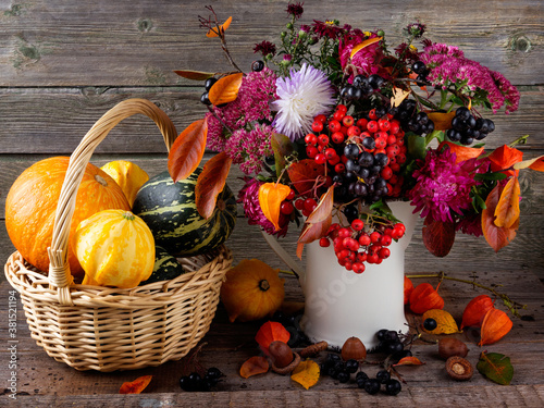 Autumn  home still life. Pumpkins and a bouquet of autumn flowers on a wooden background.