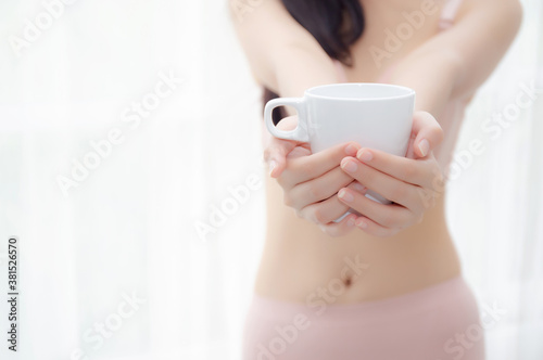 Closeup young asian sexy woman in underwear giving coffee near windows in the morning, girl with seductive figure fit serving beverage is breakfast for relax after wake up, lifestyle concept.