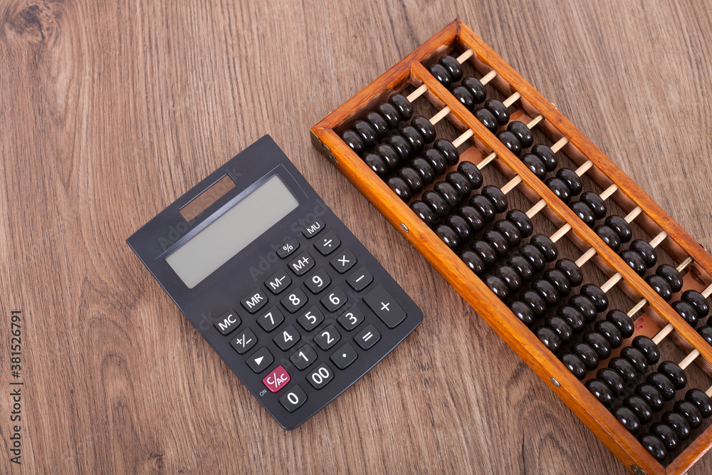 A black calculator and an abacus A black calculator and an abacus