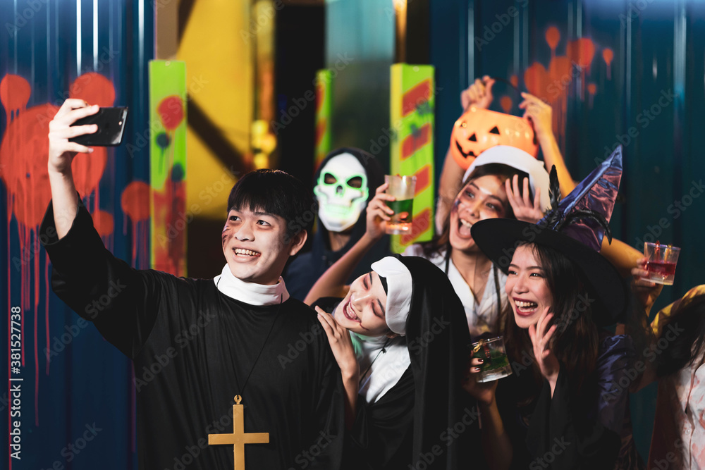 Obraz premium Group of asian friends rest in a nightclub with colored cocktails Wearing Halloween Costumes at Party in Nightclub by doing Scary faces. Celebration of Halloween