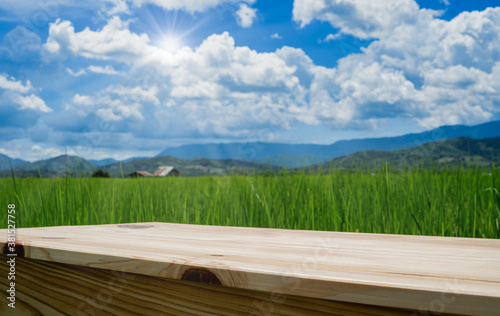 wooden table on agricultural rice field beside mountain with blue sky for use show product with copy space © lamyai