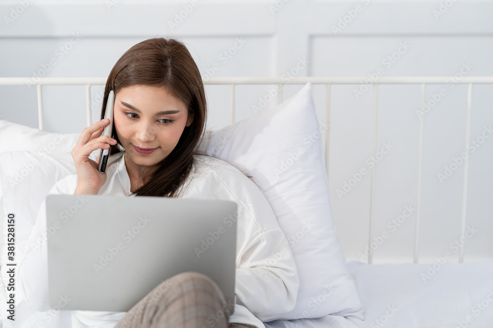 Happy casual beautiful asian woman working on laptop computer while setting on the bed in the house. Happy casual beautiful asian woman working on laptop computer while setting on the bed in the house.